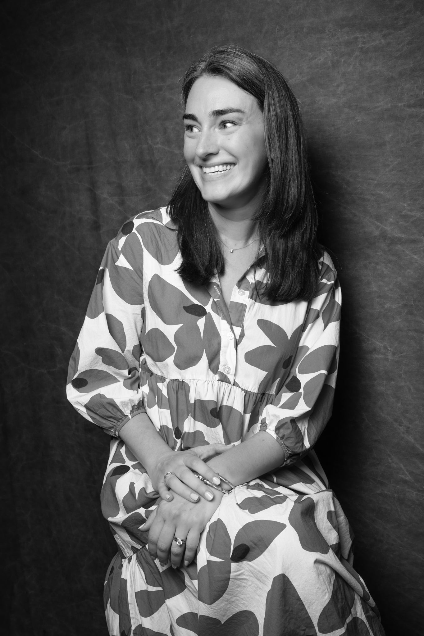 Black and white portrait of a woman wearing a patterned dress against a dark background
